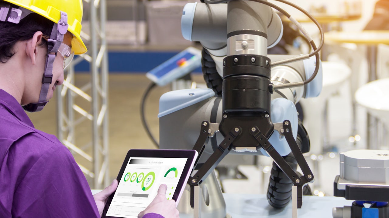 A person is standing in front of a large window with a view of a city skyline at night.