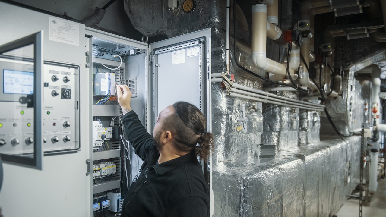 A man checks levels on a ventilation system for an indoor pool.