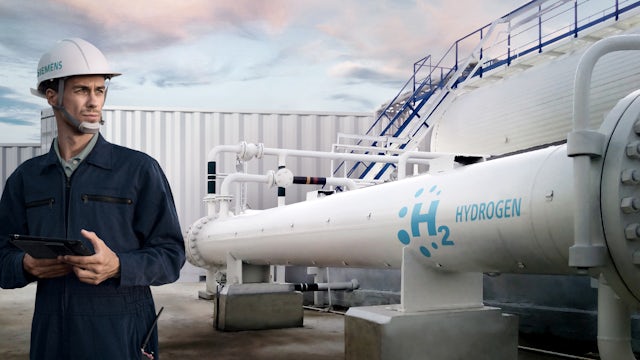 Man standing in front of a hydrogen tank and industrial pipe.