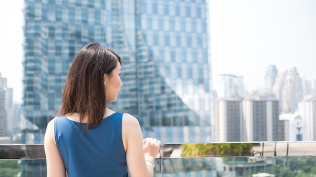 Woman looking out a balcony at a city.