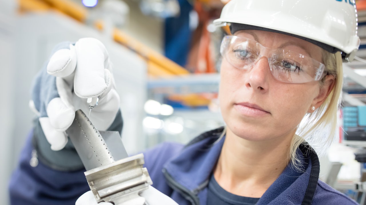 A factory worker using an additive manufacturing testing machine.