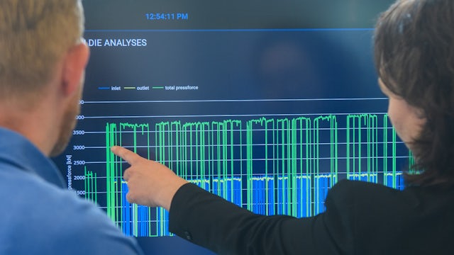 View from behind of two people pointing at a screen