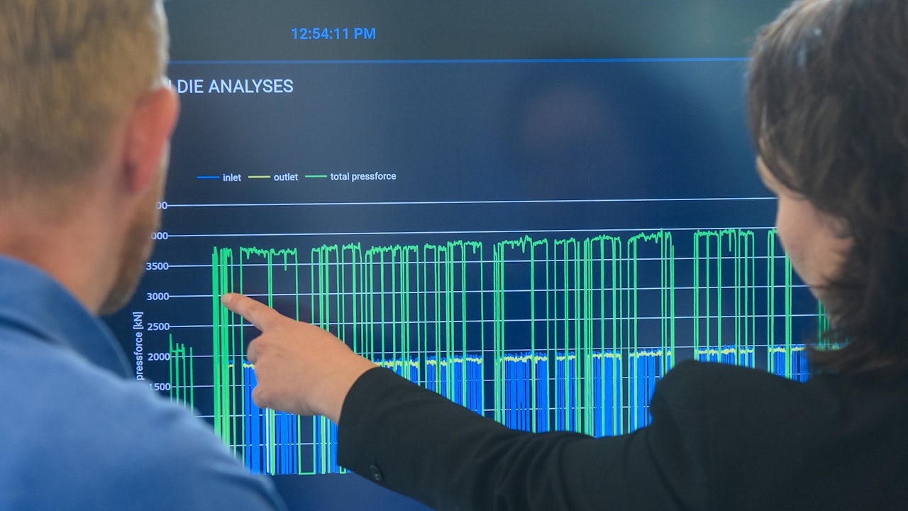 View from behind of two people pointing at a screen
