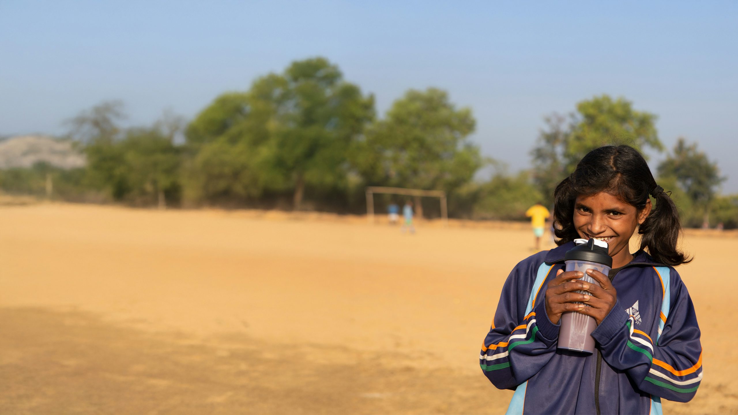 young girl drinking a protein shake in a field