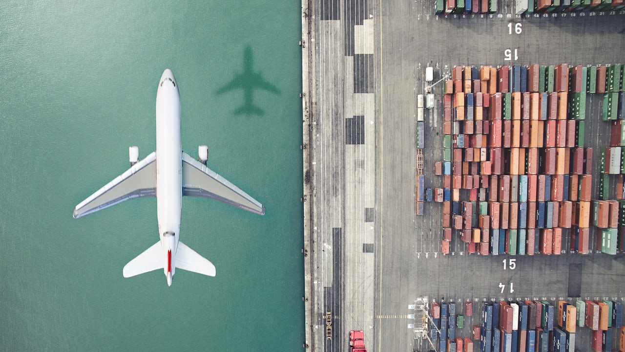 An airplane is flying over a container port.