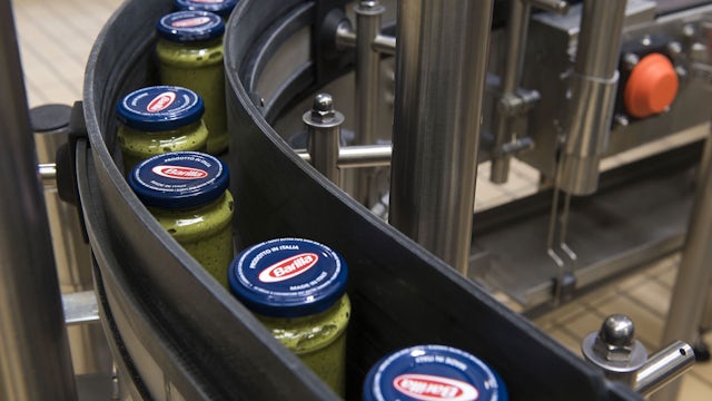 A bunch of pasta jars moving down a factory line machine.