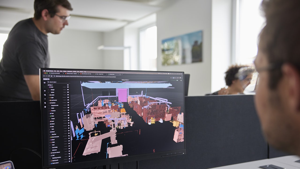 A person is standing in front of a building with a large window, holding a piece of paper with text and numbers.