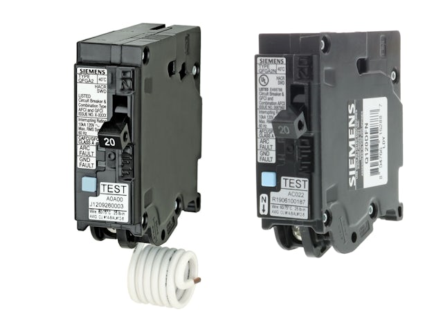 A person is standing in front of a Siemens logo, wearing a blue shirt and a white mask. 