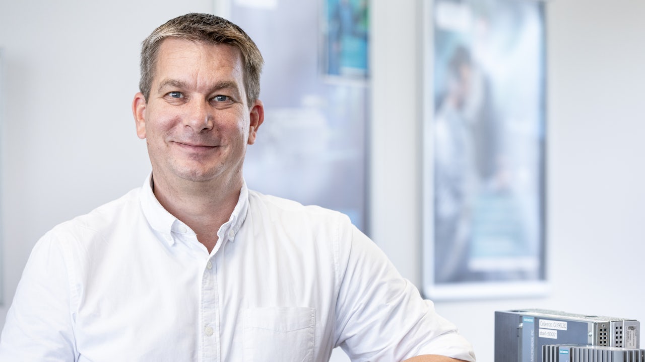 A golden retriever puppy sits on grass, looking up with bright eyes and a curious expression.
