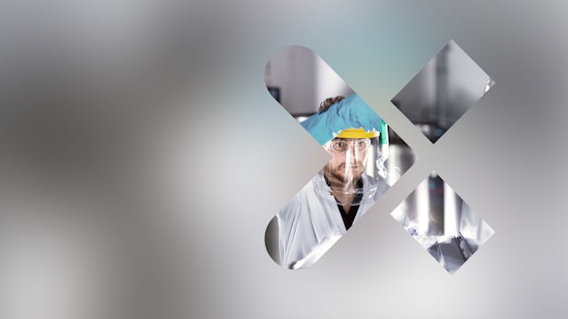 A blurry image of a pharmaceutical laboratory with a person in a lab coat working on a machine.