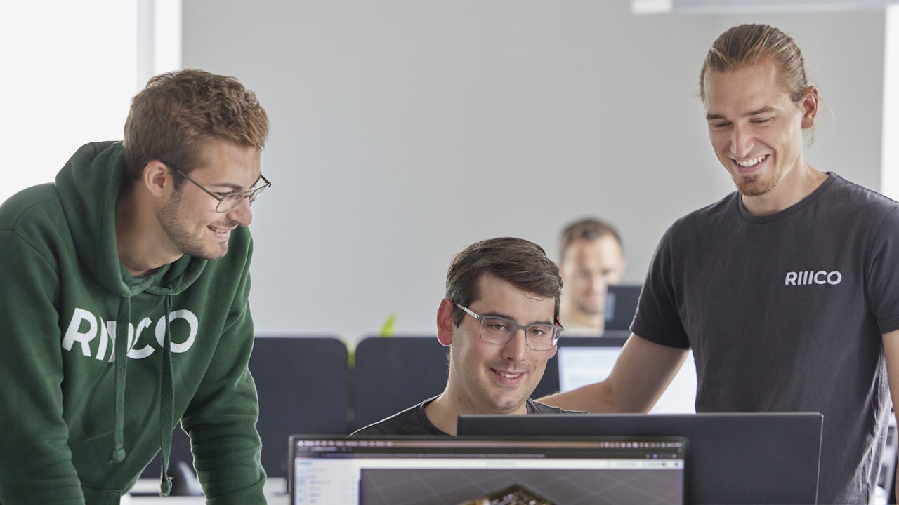 A group of people in business attire standing in front of a building with a large sign that reads 