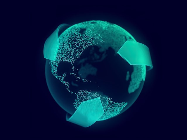 Wind turbines on a grassy hill against a cloudy sky, with a person walking in the foreground.