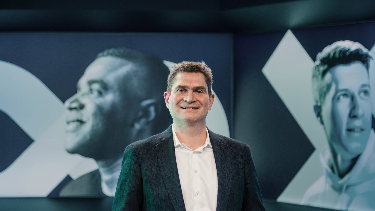 A person is standing in front of a large screen displaying a colorful abstract design.