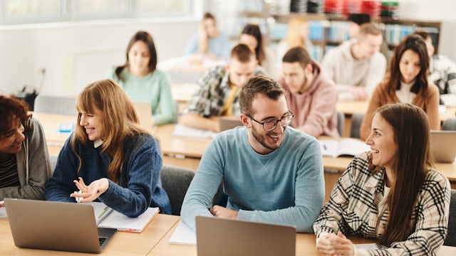 Students sitting in a classroom working on laptops during a lesson.