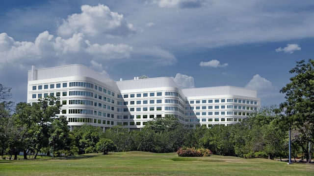 A large corporate building surrounded by trees and grass.