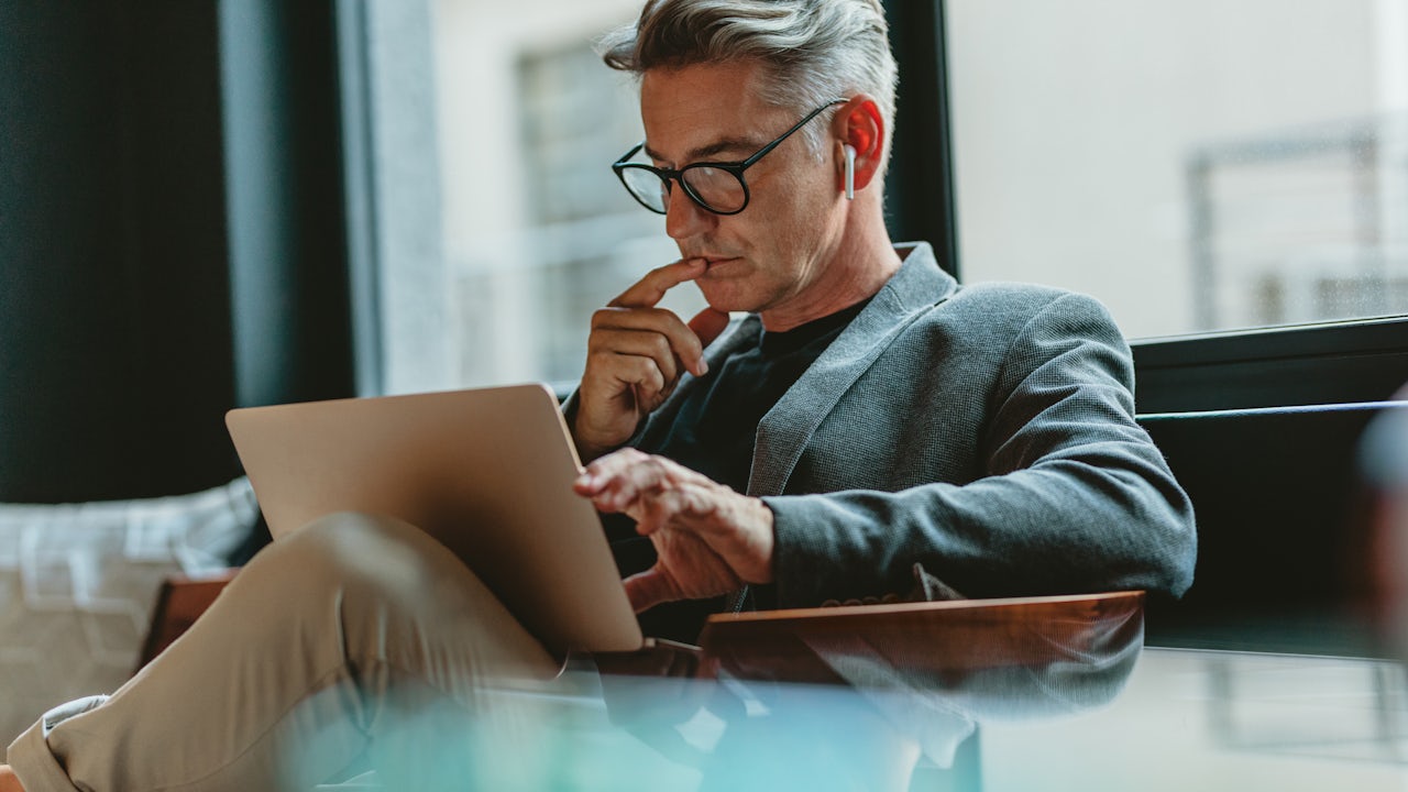 Woman in blue shirt smiling while working on laptop in office setting