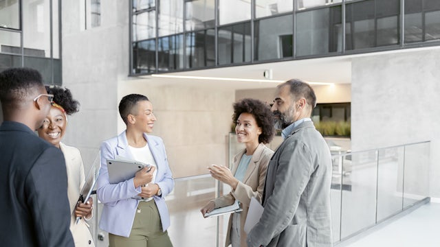 Group of colleagues standing in a circle smiling and talking.