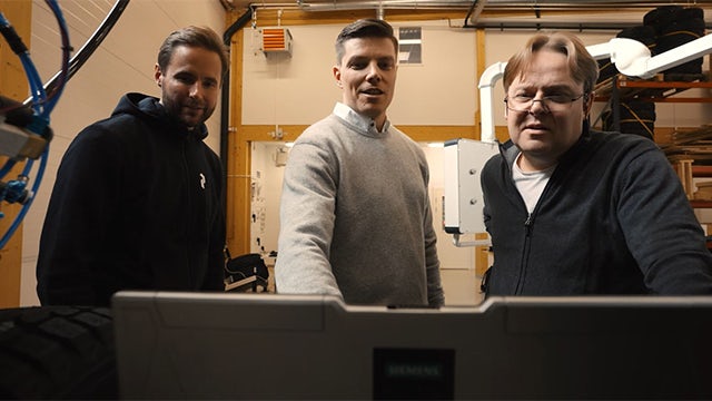 Three employees reviewing a prototype on a computer screen.