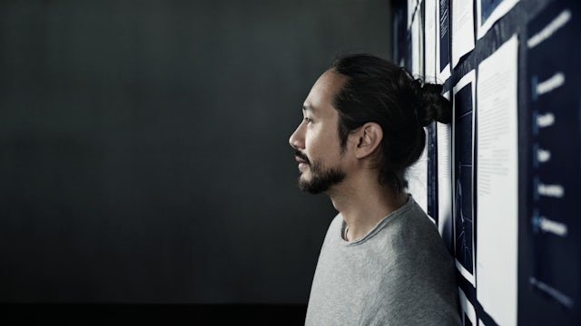 Young man leaning against a wall.