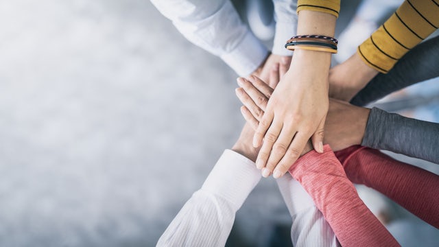 Hands stacked together signifying teamwork.