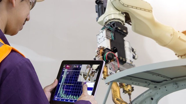 An engineer reviewing operational analytics of a robotic arm in a smart manufacturing facility