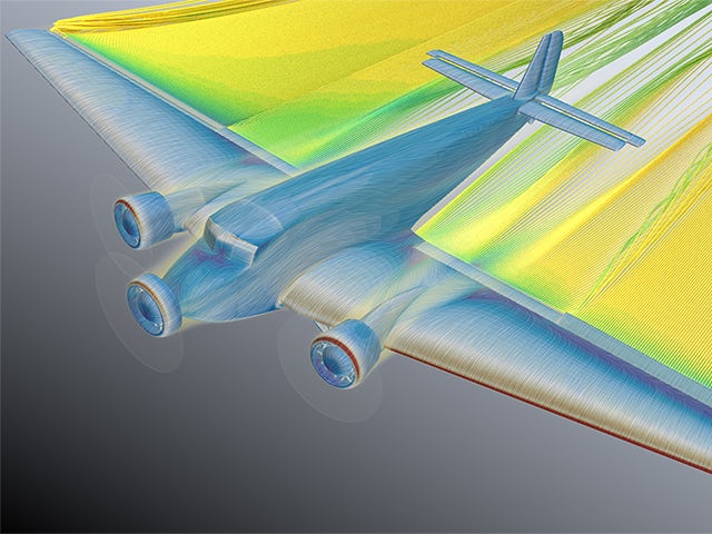 A woman in a blue shirt is standing in front of a white wall, holding a blue object in her hand.