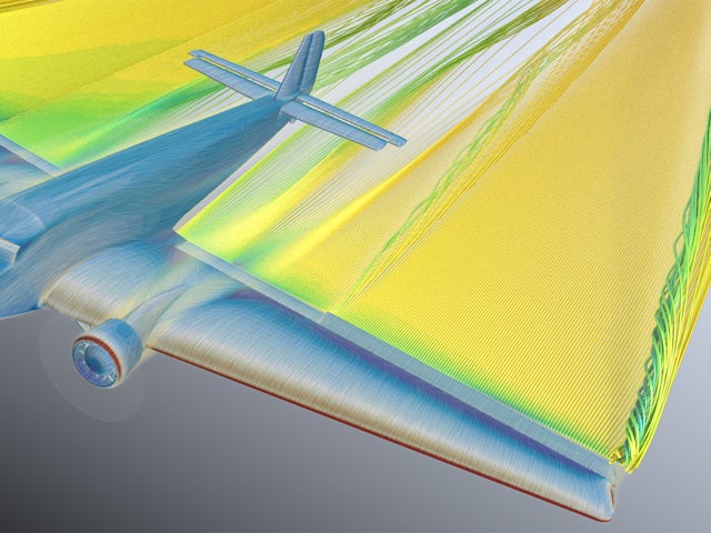 A woman in a black dress is standing in front of a white wall with a blurry background.