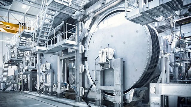 A person in a suit and tie is standing in front of a large industrial machine.
