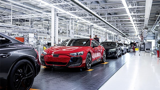 Audi factory floor with workers assembling cars.