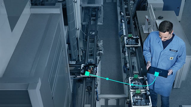 A person is working on a computer with a robot arm beside them.