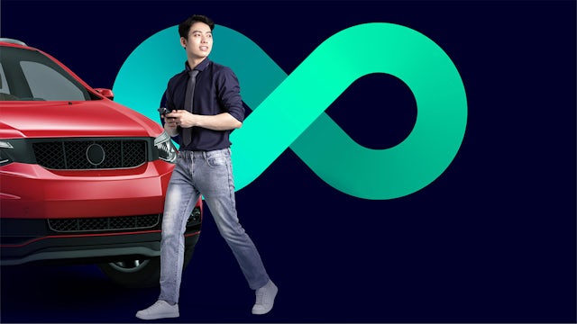 A young Asian man walks in front of a red vehicle.