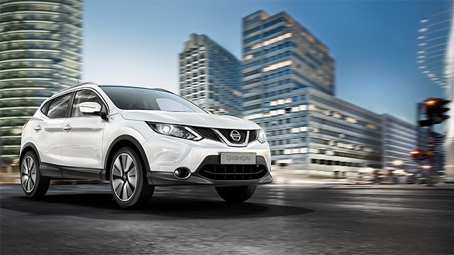 A Nissan car is displayed in a showroom with a spotlight on it.