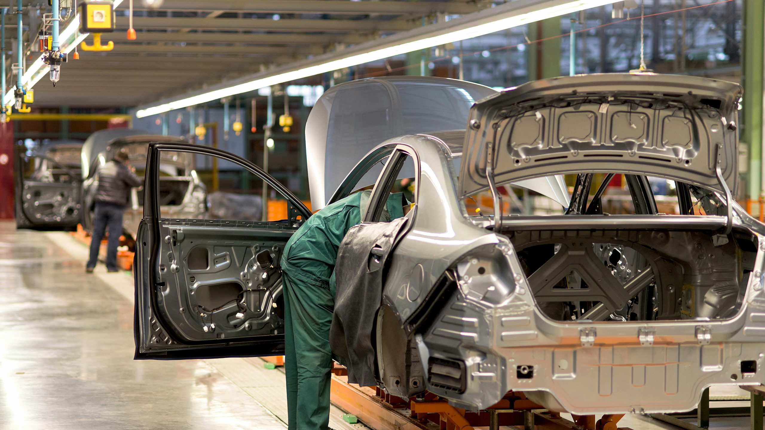 An image of an automotive production line with workers assembling cars on a conveyor belt.