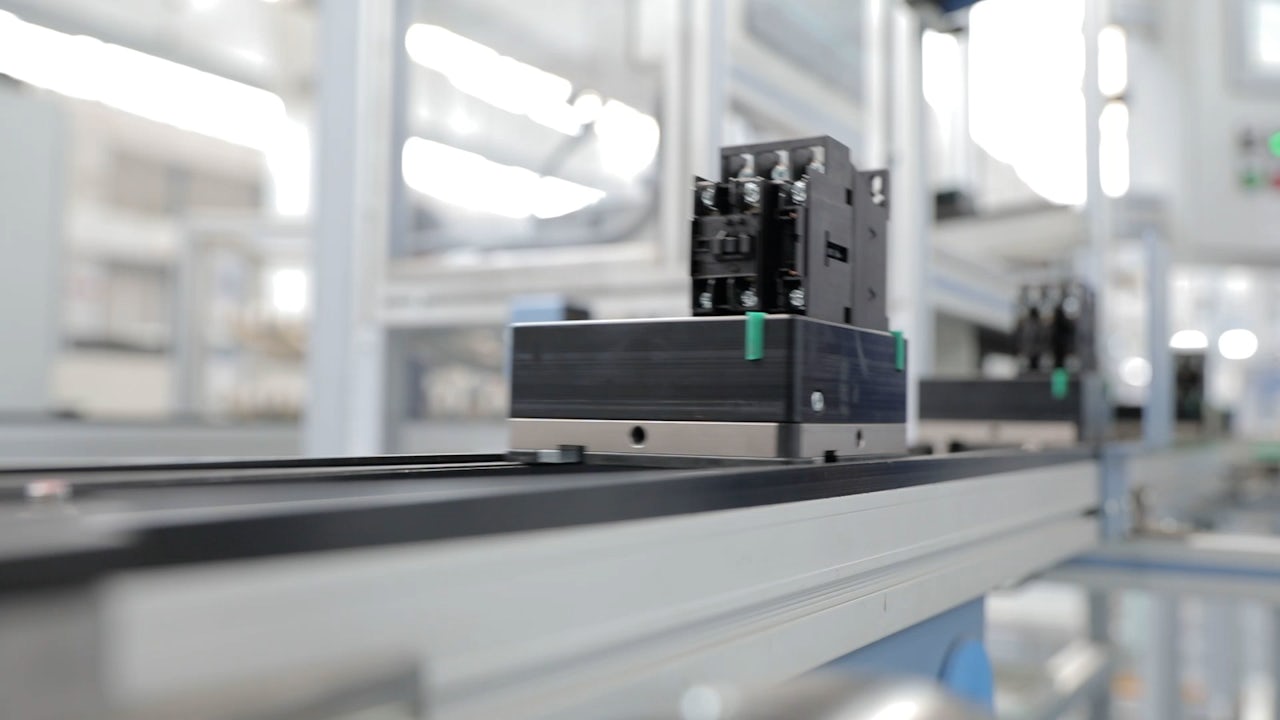 Person in black shirt standing against white wall, holding a dark object with blurred background.