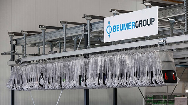 The image shows a modern industrial facility with a large building and machinery visible.