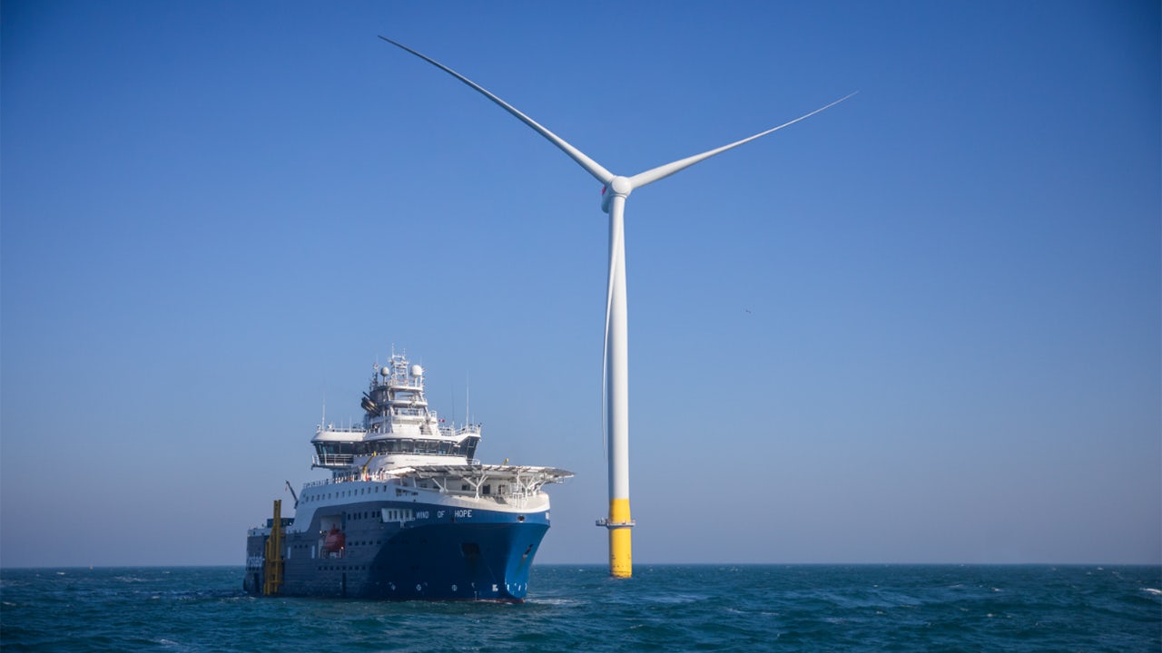 Offshore service vessel near a large wind turbine in open water.
