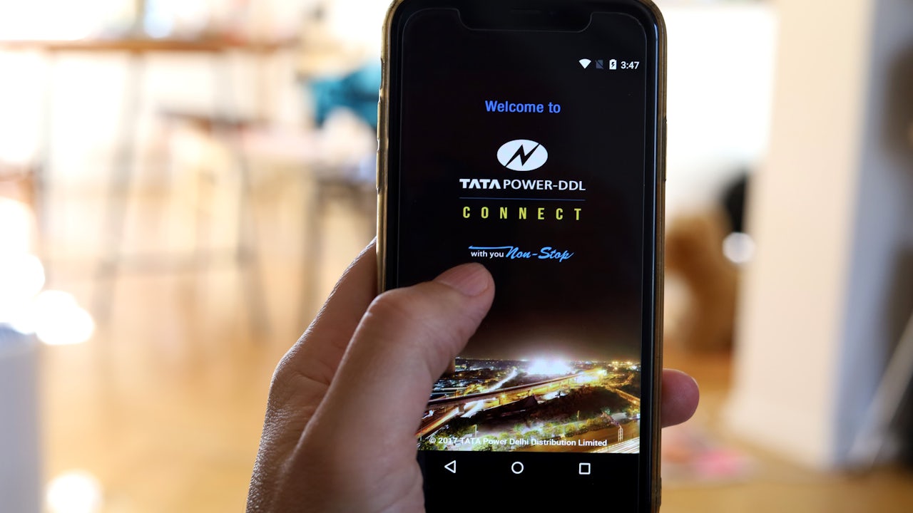 Close-up of a hand holding a smartphone displaying the Tata Power-DDL Connect app.