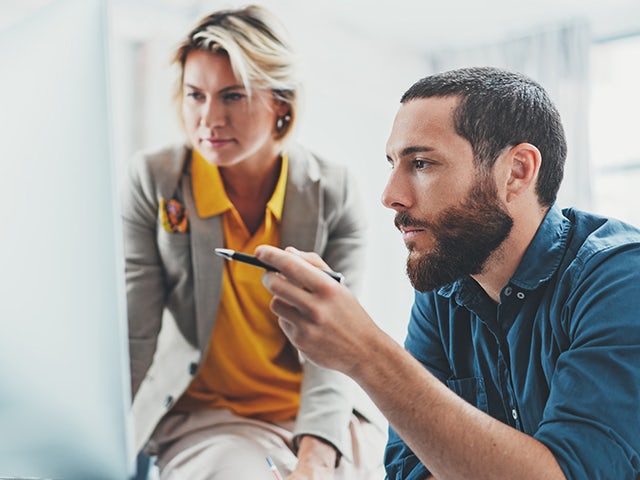 Man and woman looking at a screen, pointing.