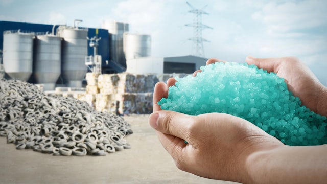 A handle holding small bead-like material, with a tires and recycled material in the background.