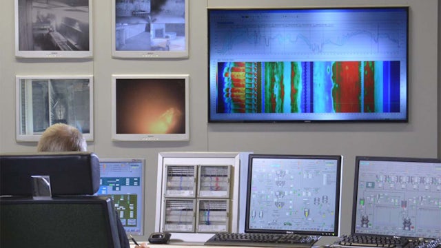 Person interacting with cement process control system interface on multiple desktop screens.