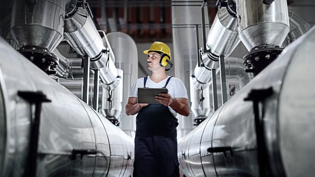 A digital worker in a chemical industry setting is using a tablet computer.