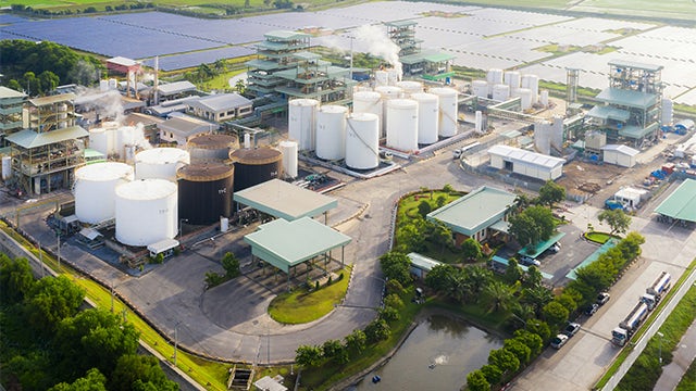 Industrial facility with large metal tanks and pipes against a blue sky