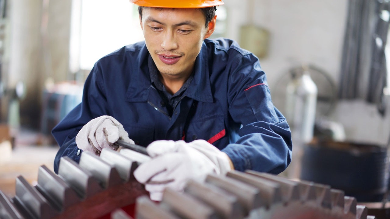 A man working on gears on a production line.