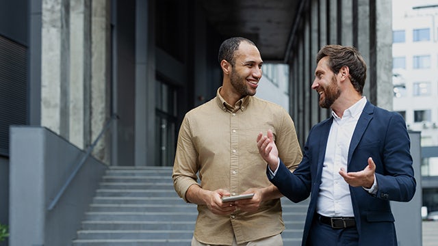 People walking outside an office building, possibly discussing sustainability and integrity.