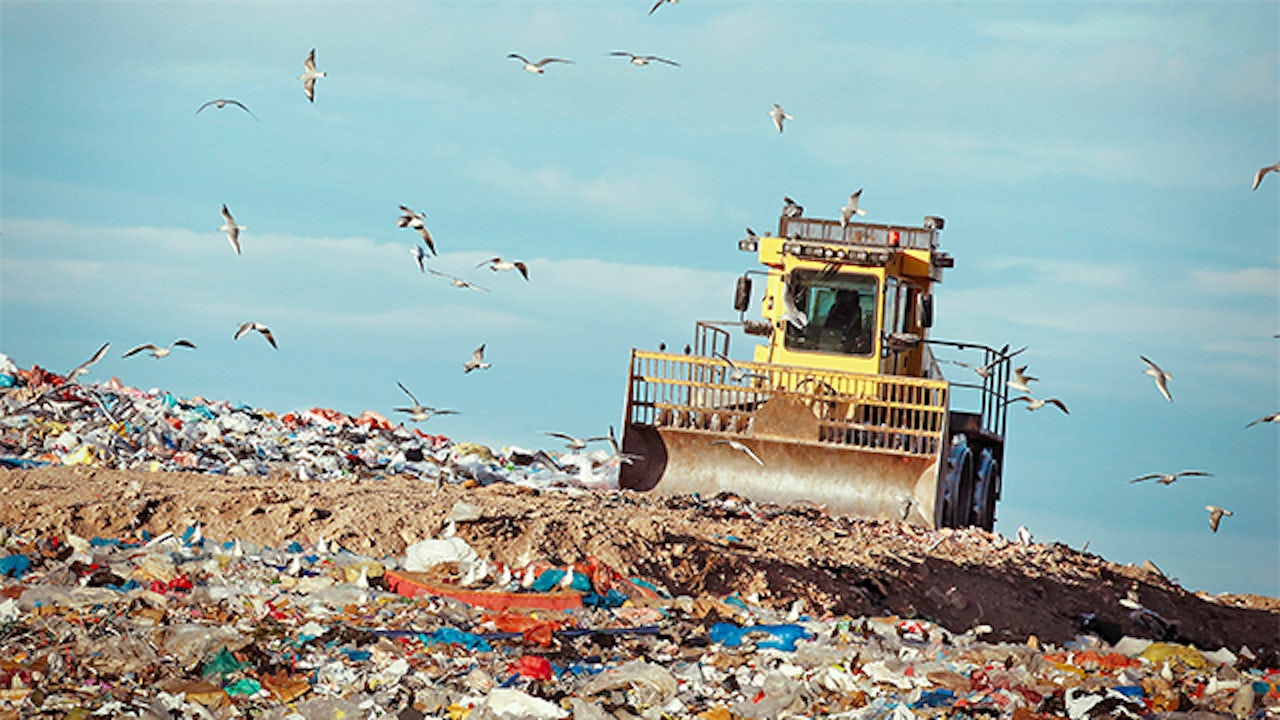 A garbage compactor machine is compressing waste in a garbage dump.