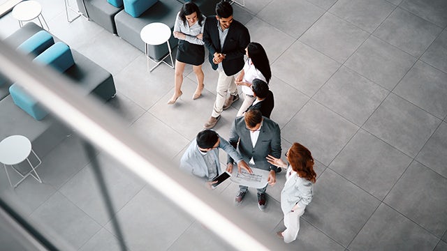 Group of people standing and talking in an office.