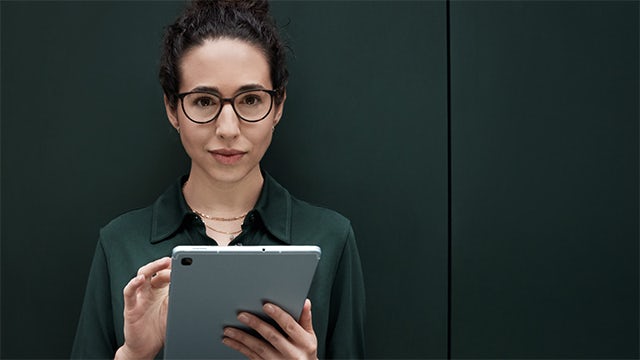 Woman holding tablet device and staring at you.