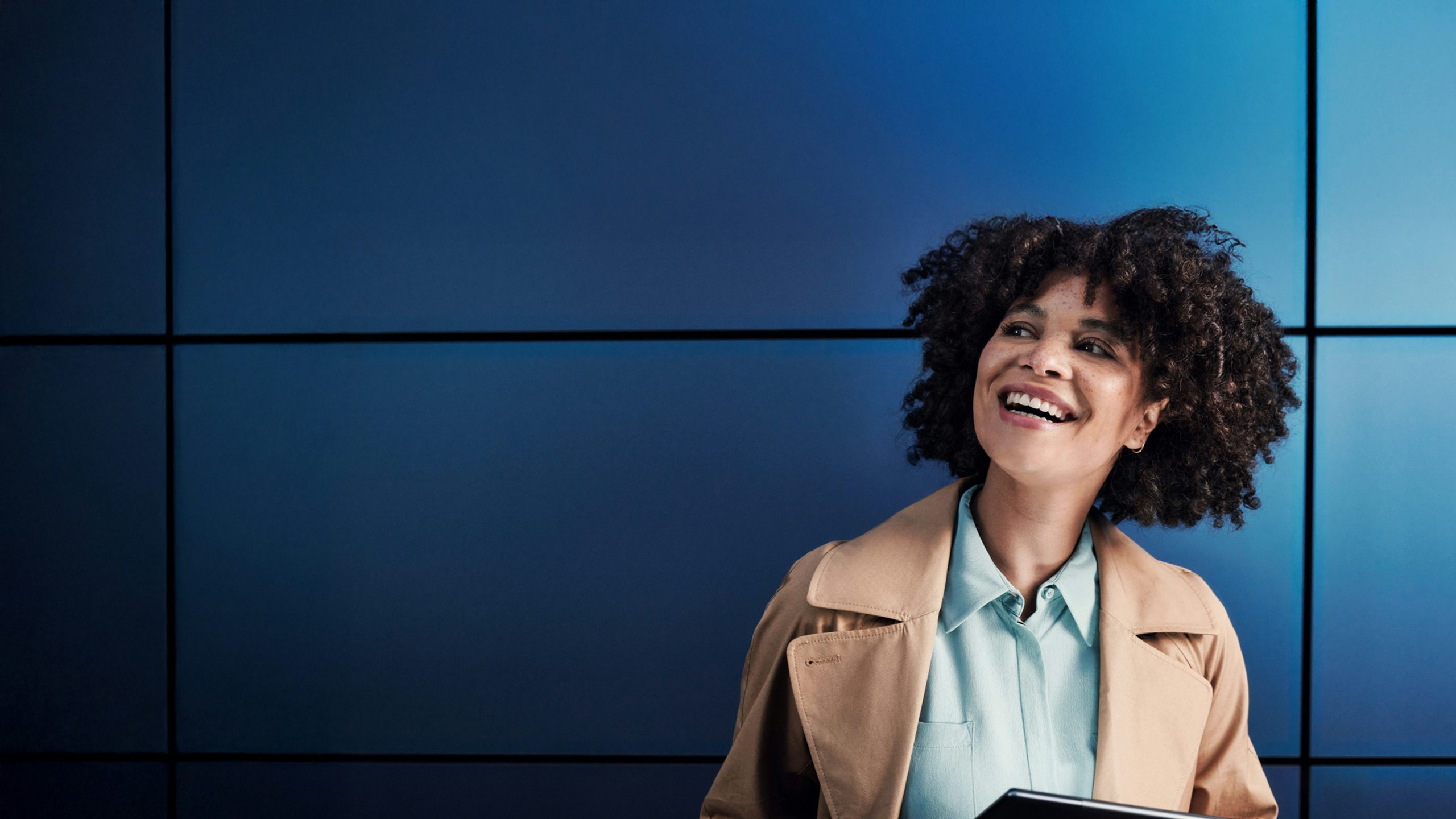 Woman looking up from her tablet device and smiling.