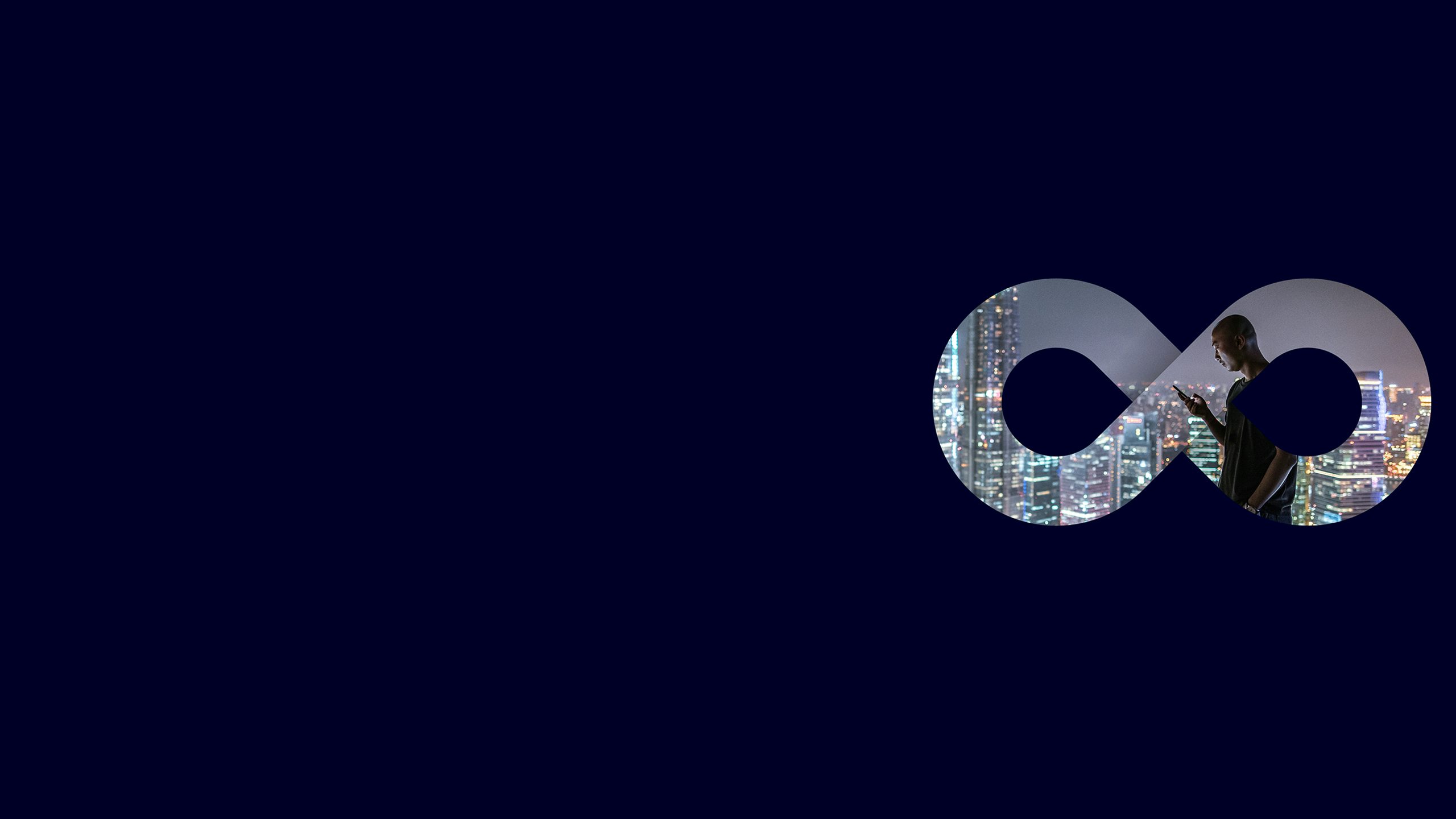 A person wearing a headset smiles while working at a computer in an office setting.