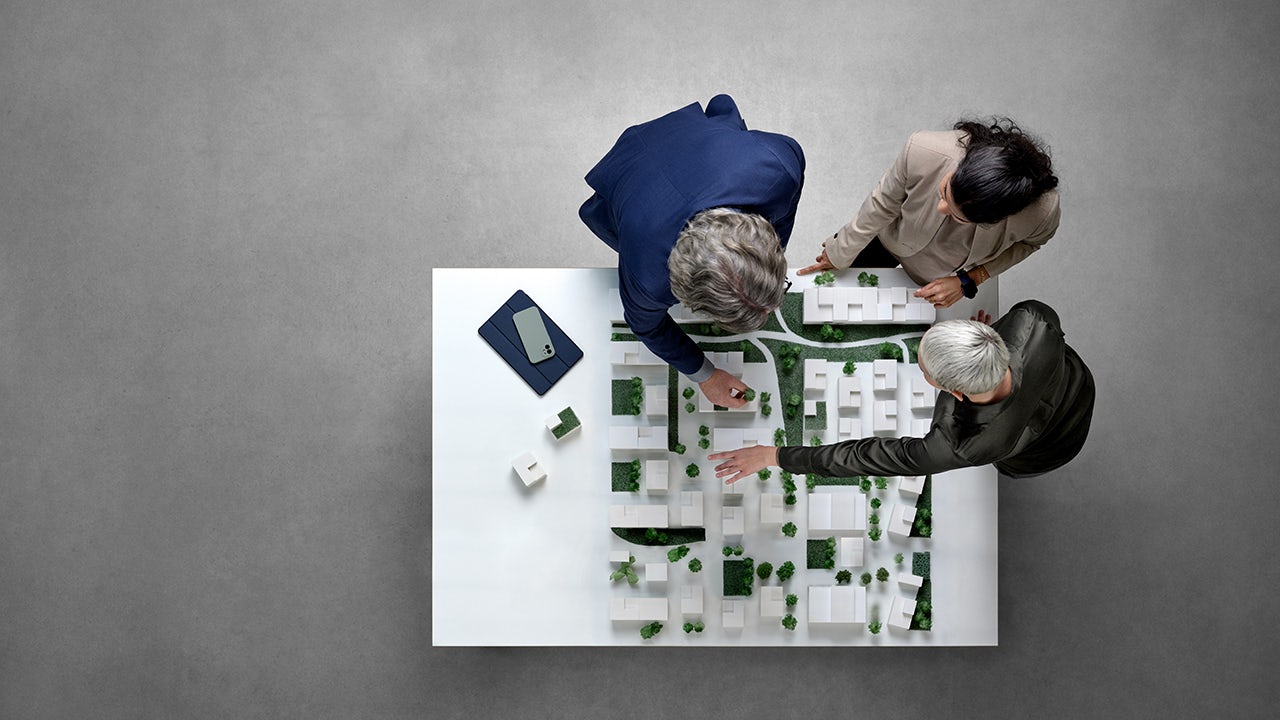Top view of a group of city planners reviewing a scale model of a subdivision.